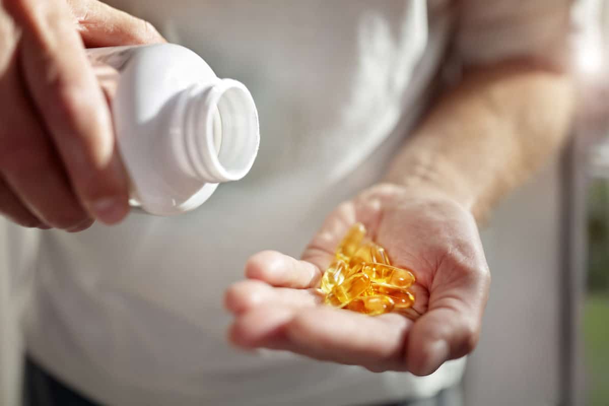 Man pouring out capsules of Vitamin D at home to help with his IBD issues.