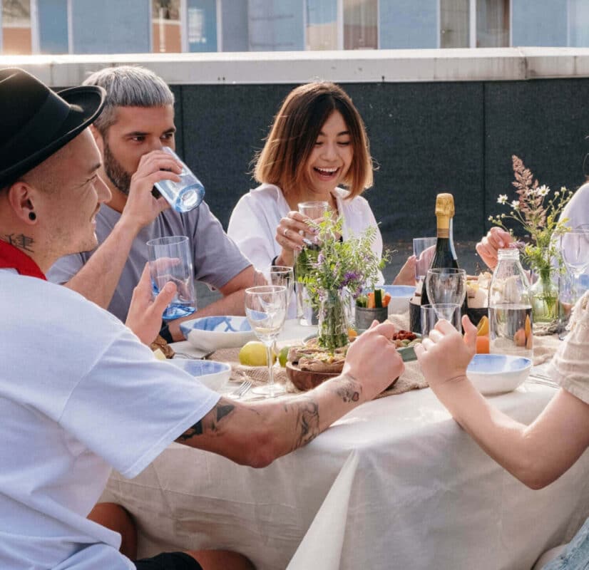 A group of friends laugh together and eat a spread of food outside on a rooftop, Crohn's and Colitis Dietitians nutrition therapy for IBD