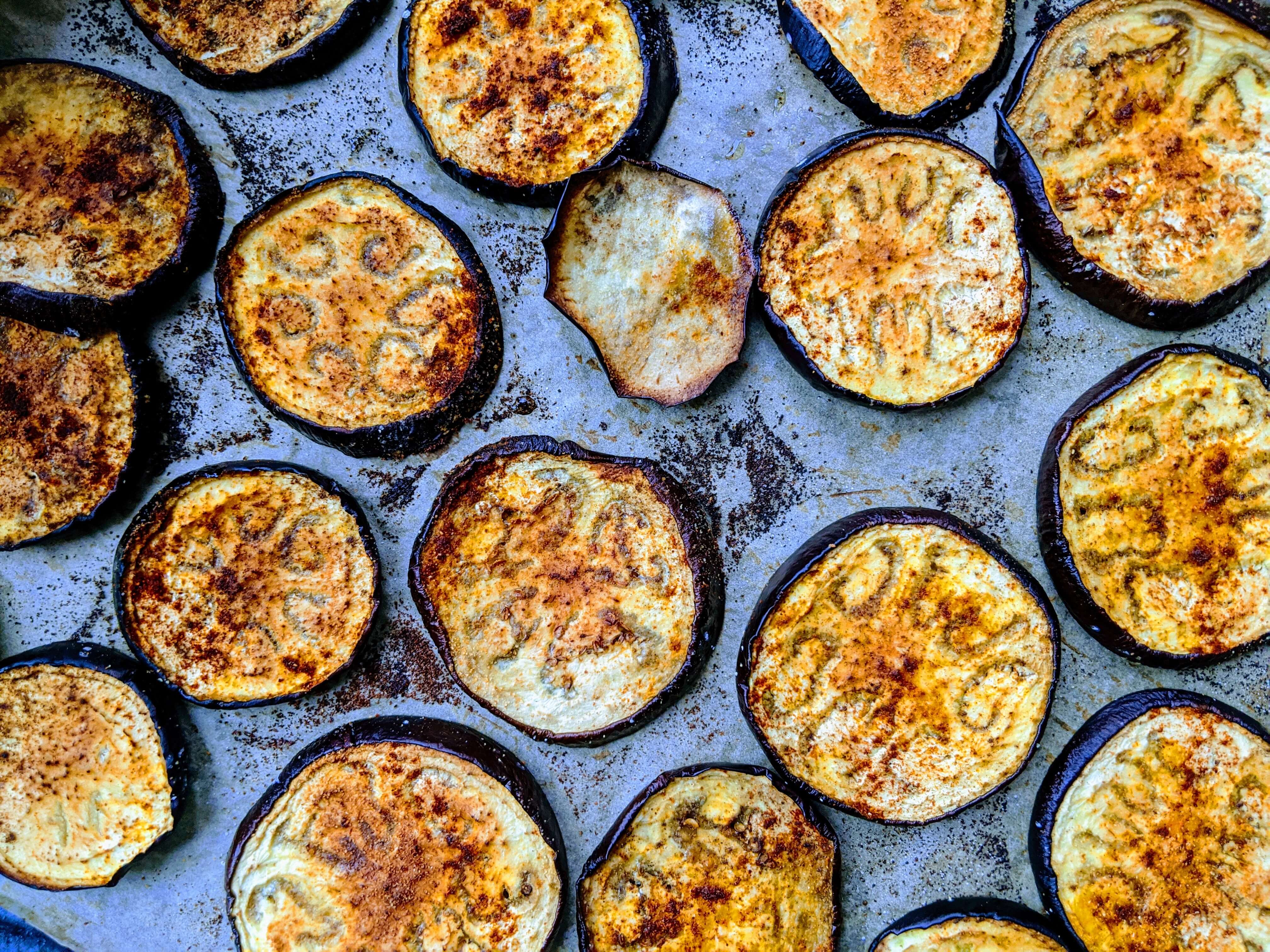 Sliced eggplant seasoned and spread out on a baking tray
