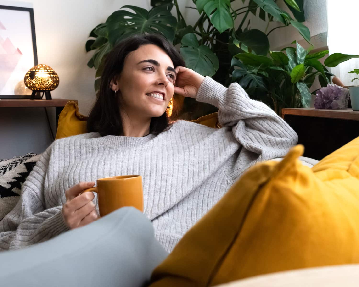 Woman rests on her couch, sips from a mug and looks calmly into the distance, what to eat with IBD